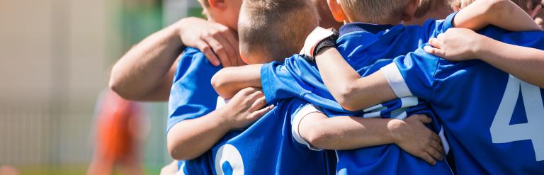 A group of kids playing sport in a huddle